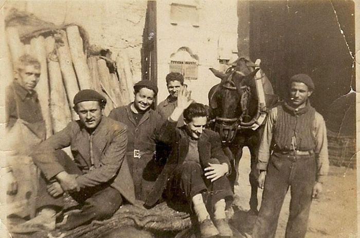 Un grupo de hombres posa para una foto con un caballo al fondo.