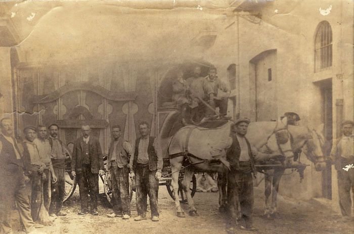 Un grupo de hombres está de pie junto a un carruaje tirado por caballos.