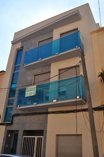 Edificio de apartamentos alto de color beige con barandillas azules en los balcones y una red azul que cubre dos plantas.