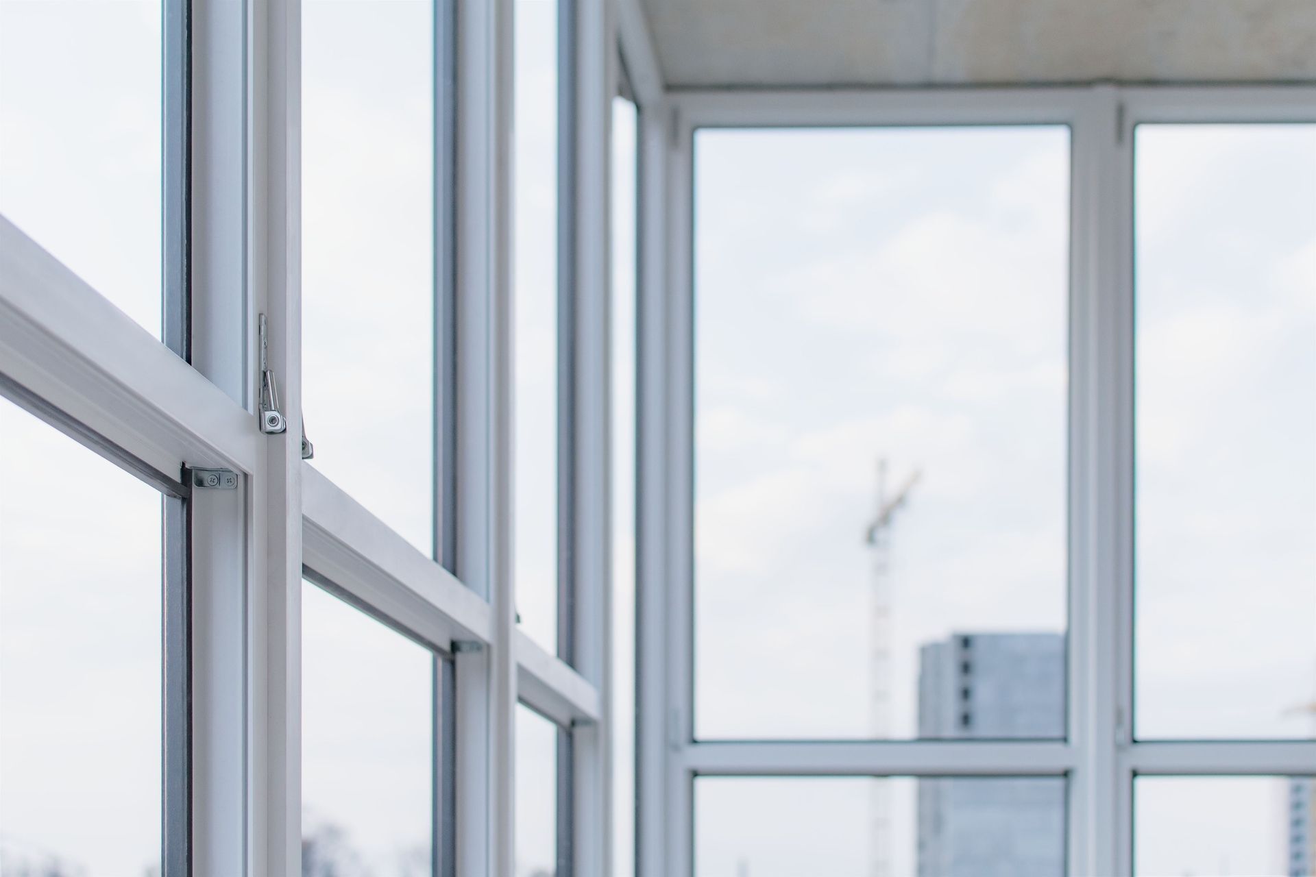 Ventanas con marco blanco con un cielo nublado y una construcción lejana al fondo.