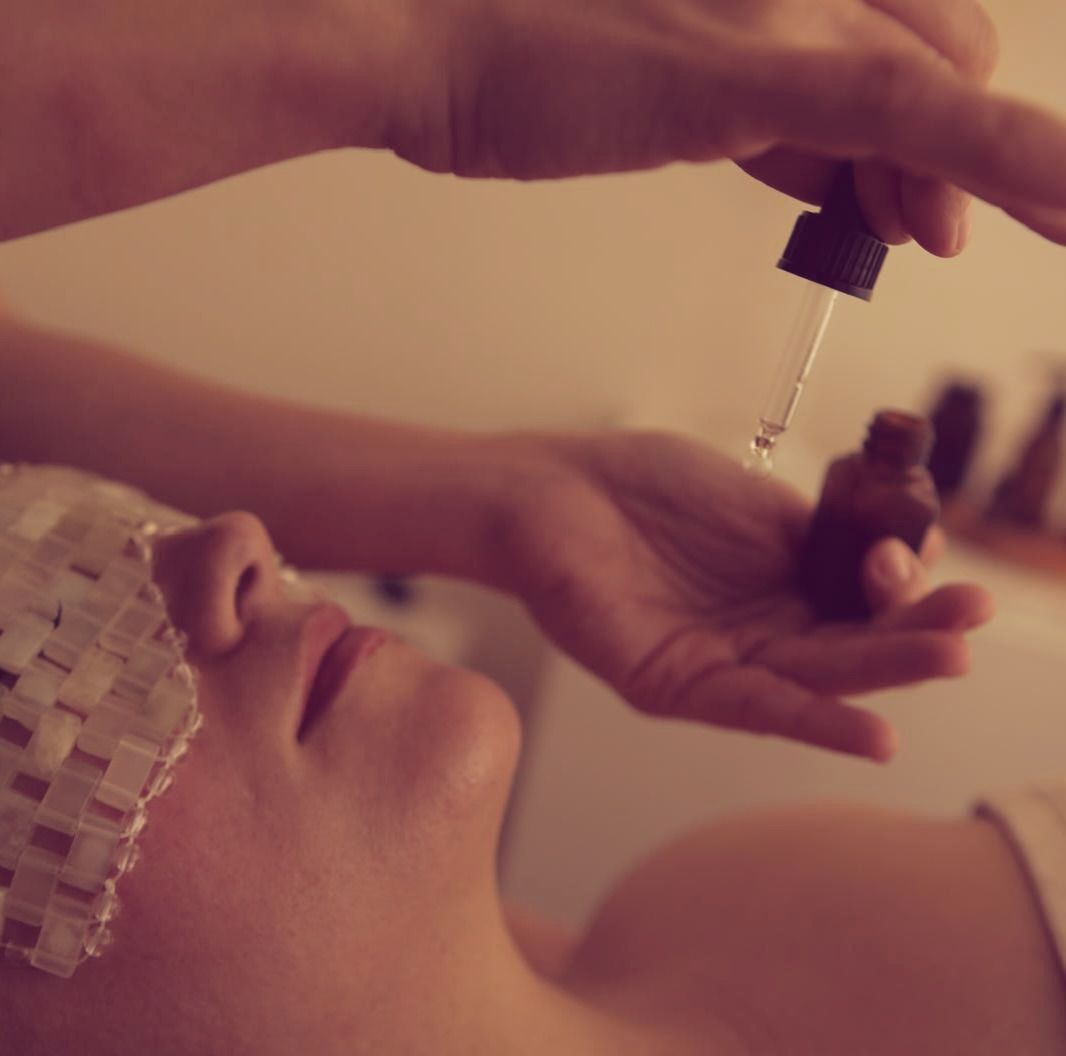 Tratamiento de spa que consiste en aplicar gotas de aceite en el rostro de una mujer con una toalla