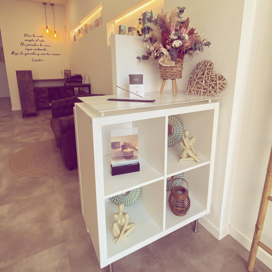 Pasillo luminoso y minimalista con una estantería blanca con compartimentos, un arreglo floral seco