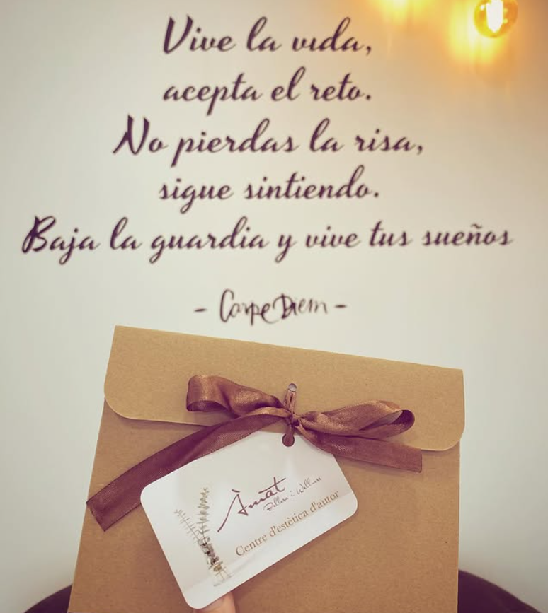Frase motivacional en la pared sobre una caja kraft con lazo morado y una tarjeta colgante.