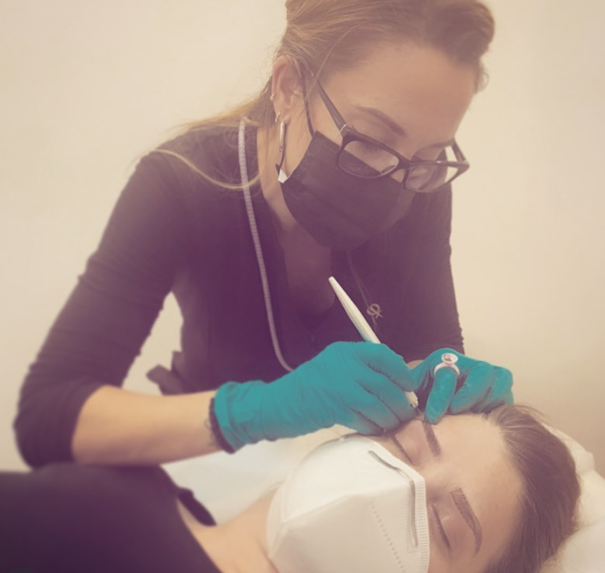 Un profesional dental, vestido con bata negra y guantes azules, atiende a un paciente que lleva mascarilla.