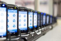 Une rangée de smartphones sur des supports affichant des icônes d'applications, se perdant au loin à l'intérieur.