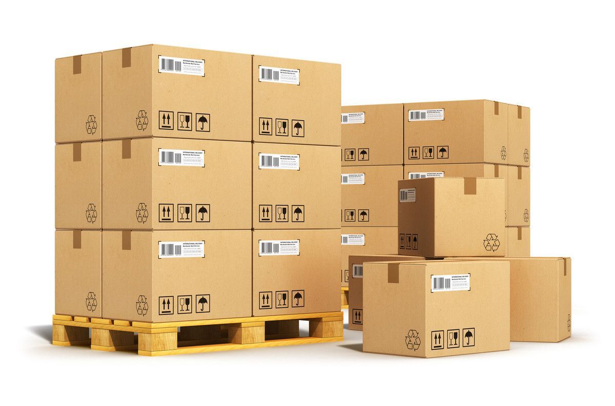 Des cartons bruns empilés sur des palettes en bois, avec deux boîtes séparées à côté.