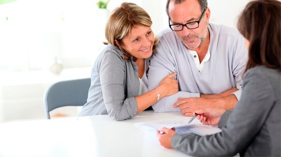 Pareja revisando documentos con un profesional en un entorno de oficina.