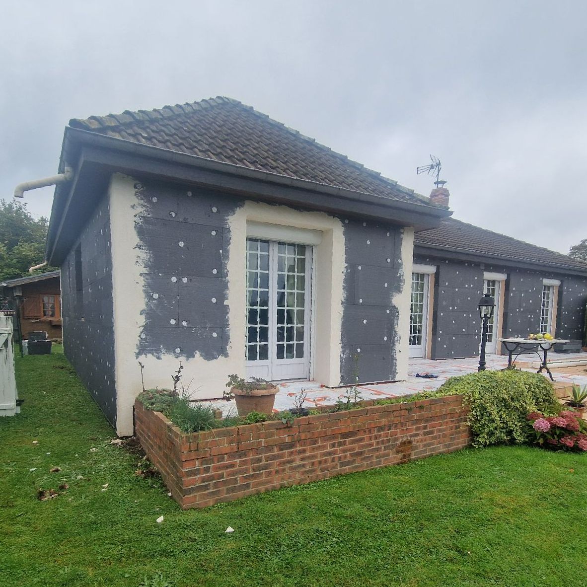 Maison avec plaques d'isolant et un muret de briques rouges devant
