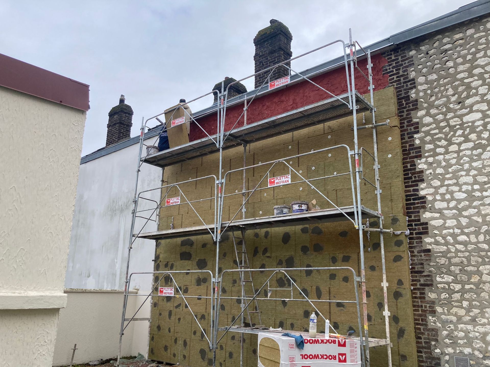 Façade de maison à trois étages en brique rouge et en crépi beige