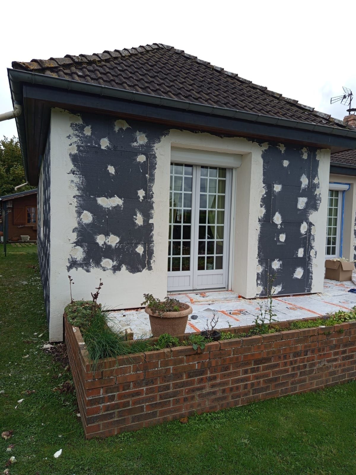 Muret rouge devant maison en construction