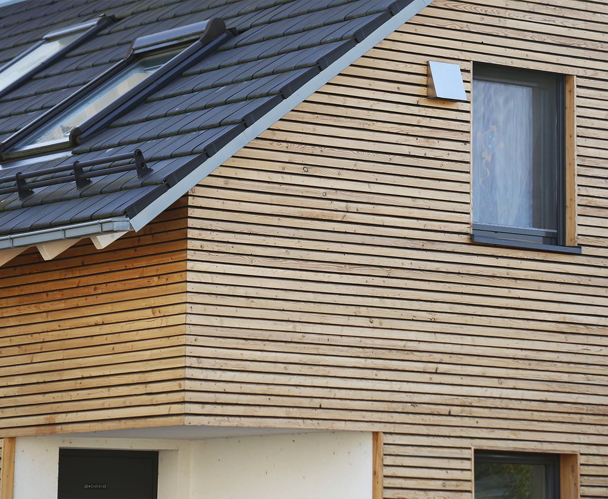 Maison avec bardage en bois clair et toiture foncée