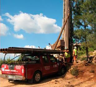 Un camión rojo está estacionado al lado de una plataforma de perforación.