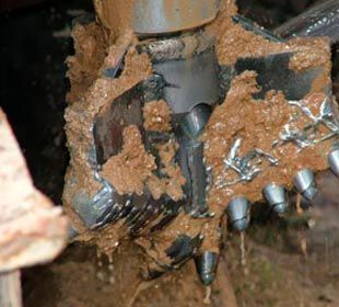 Un primer plano de una broca cubierta de barro.