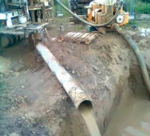 Se utiliza una tubería para bombear agua a un agujero en el suelo.