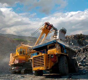 Un gran camión volquete amarillo está siendo cargado con rocas en una cantera.