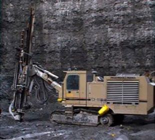 Una gran excavadora está situada delante de una gran pared de roca.