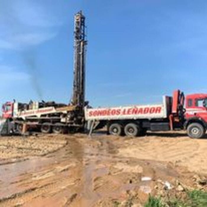 Un camión está estacionado al lado de una plataforma de perforación en un campo fangoso.