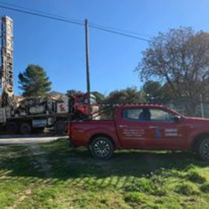 Un camión rojo está estacionado en un campo de hierba al lado de un camión.