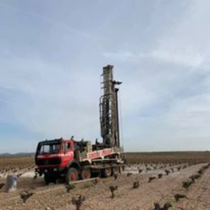 Un camión rojo está estacionado en medio de un campo de tierra.