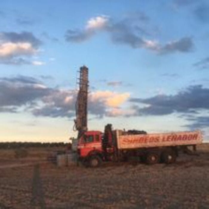 Un camión con una grúa encima está estacionado en un campo.