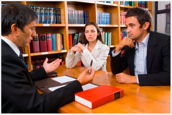 Un hombre y una mujer están sentados en una mesa hablando con un abogado.