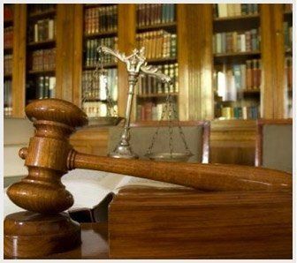 Un mazo de madera y una balanza de la justicia están sobre una mesa en una sala del tribunal.