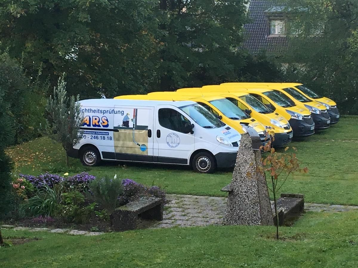 Eine Reihe gelber Lieferwagen parkt auf einer Rasenfläche