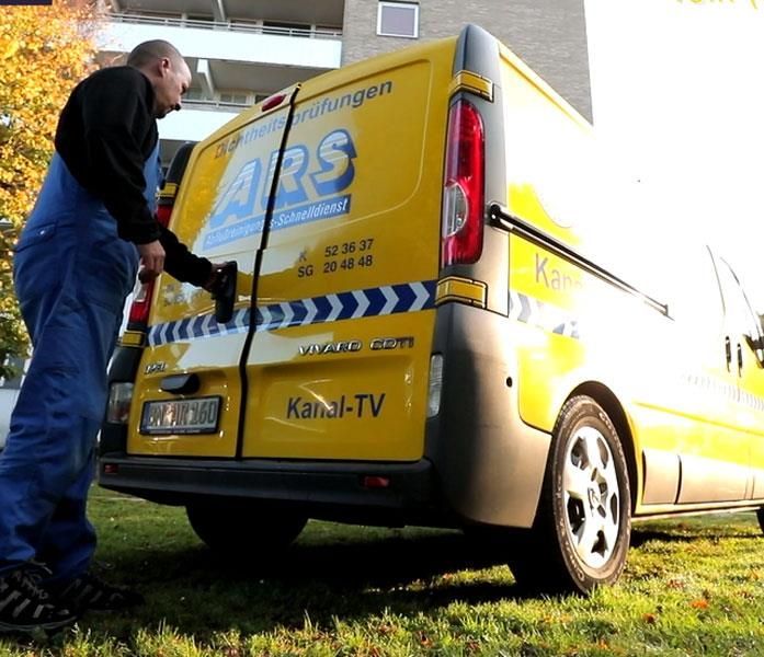 Ein Mann steht neben einem gelben Lieferwagen mit der Aufschrift „ars“