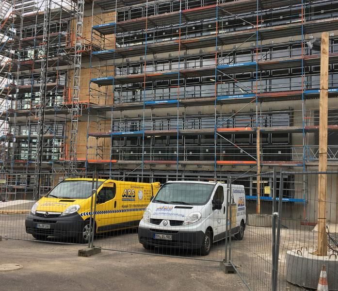 Zwei Baufahrzeuge stehen vor einem im Bau befindlichen Gebäude