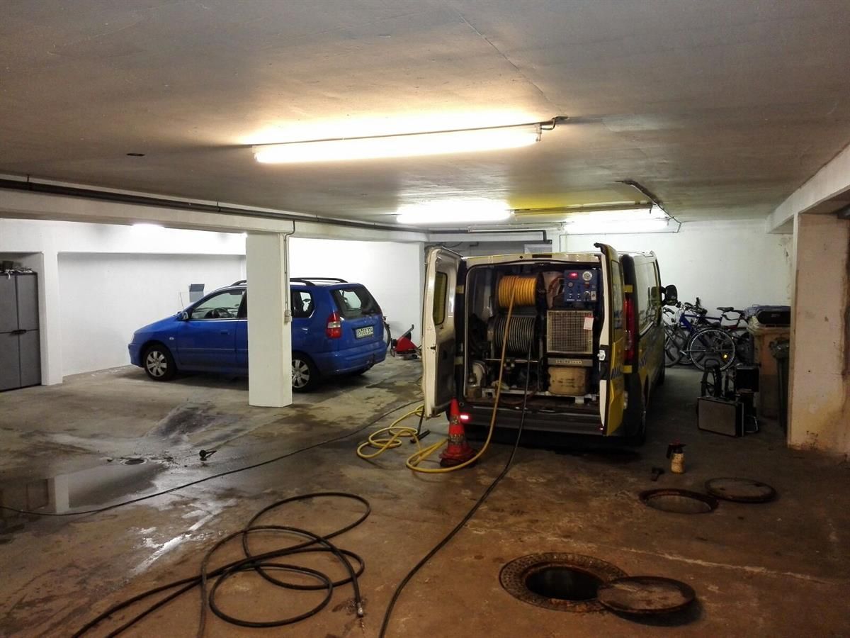 Ein blaues Auto steht in einer Garage neben einem Lieferwagen