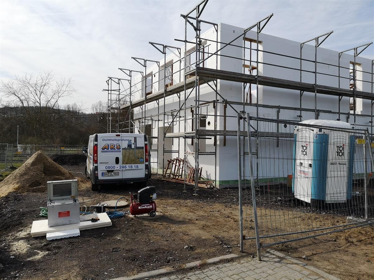 Ein weißer Lieferwagen steht vor einem im Bau befindlichen Gebäude