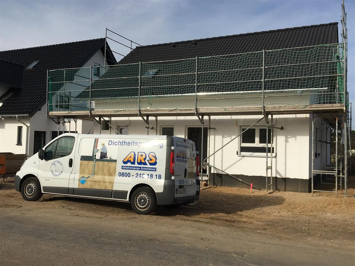 Ein Ars-Van steht vor einem im Bau befindlichen Haus