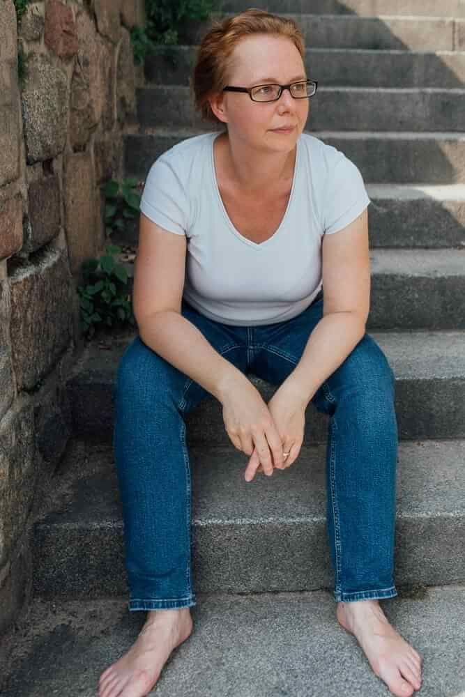 Martina sitzt barfuss auf einer Steintreppe