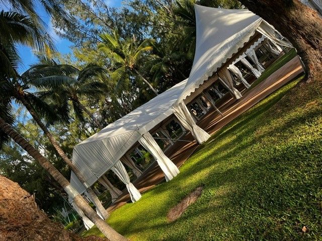 Plusieurs tentes pliables et barnum sur un terrain à côté d'une colline.