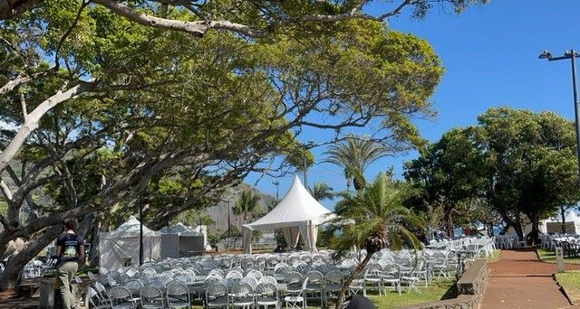 Plusieurs chapiteaux et plusieurs chaises sur un terrain pour un événement