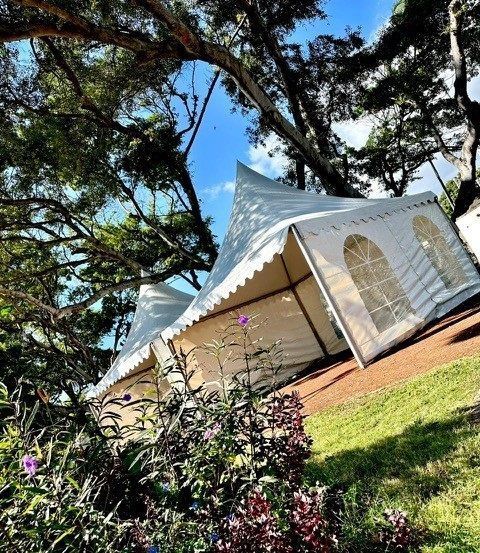 Deux tentes chapiteaux autour de grands arbres.
