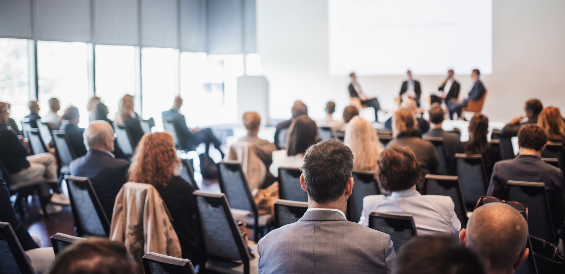 Une conférence avec du public et des hommes qui discutent sur une estrade