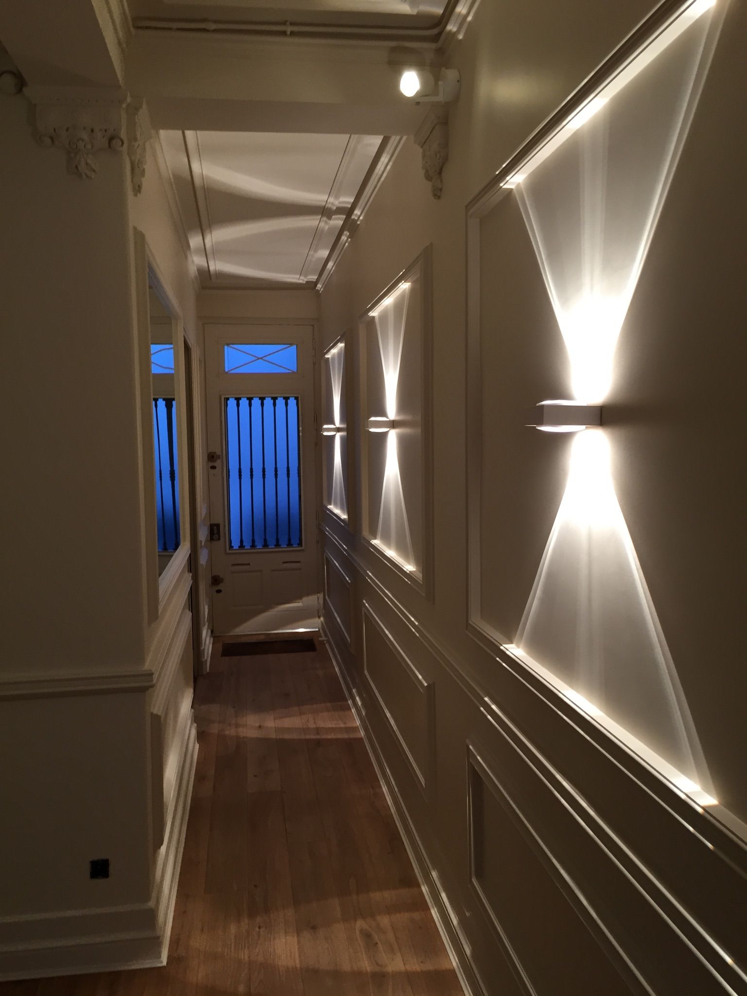 Un couloir avec des luminaires fixés sur les murs.