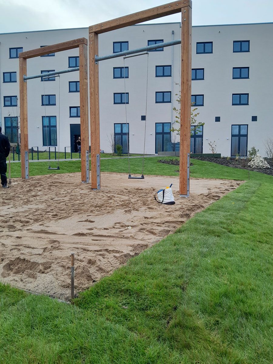 ein Holzgebäude mit einem Zaun davor und einem Traktor dahinter - Spielplatzprüfung Franziska Müller aus Lüchow im Wendland