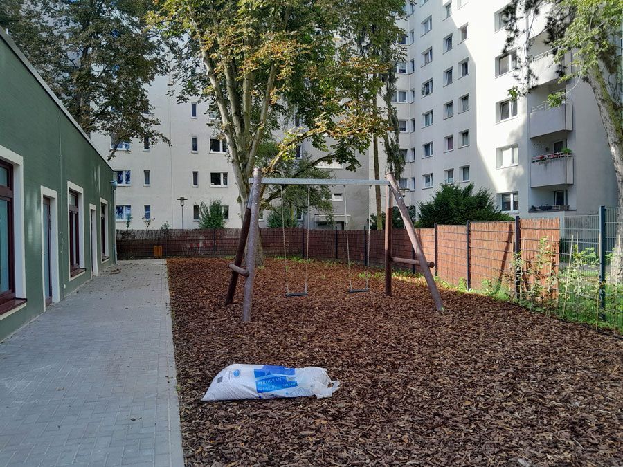 ein Holzgebäude mit einem Zaun davor und einem Traktor dahinter - Spielplatzprüfung Franziska Müller aus Lüchow im Wendland