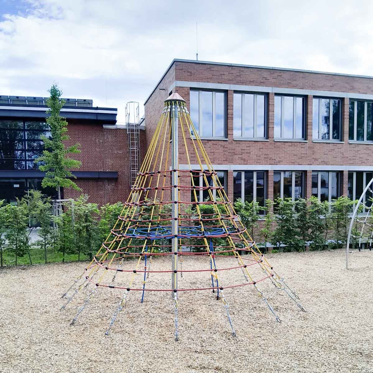 ein Klettergerüst in einem Spielplatz vor einem Backsteingebäude - Spielplatzprüfung Franziska Müller aus Lüchow im Wendland