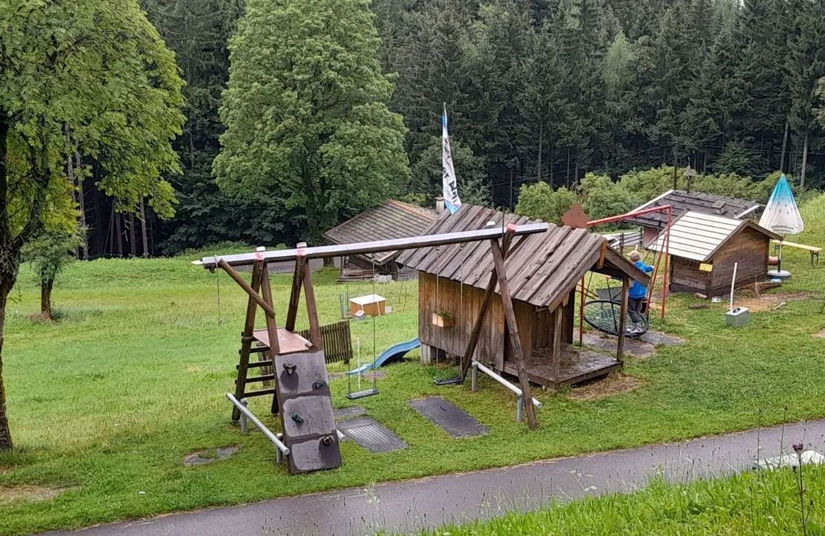ein Holzspielplatz mit Schaukeln und Hütten in einem Feld - Spielplatzprüfung Franziska Müller aus Lüchow im Wendland