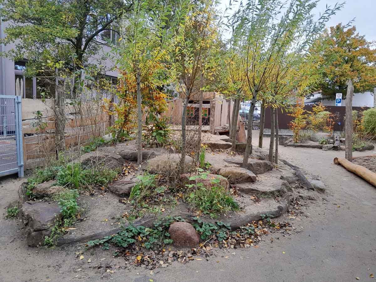 ein Garten mit Bäumen und Felsen in der Mitte - Spielplatzprüfung Franziska Müller aus Lüchow im Wendland