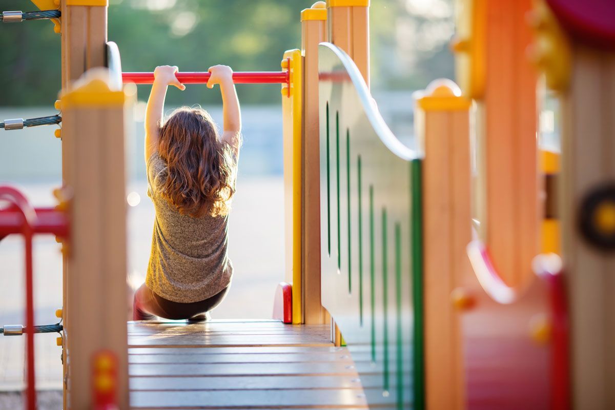 Ein kleines Mädchen hängt an einer horizontalen Bar auf einem Spielplatz - Spielplatzprüfung Franziska Müller aus Lüchow im Wendland