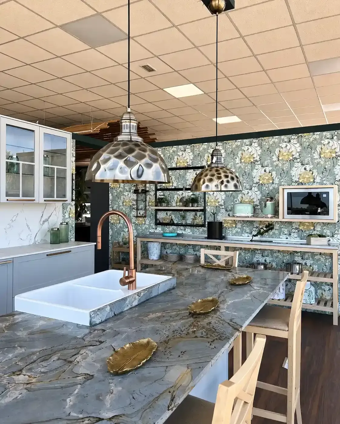 Cocina moderna con isla de mármol, lámparas colgantes y salpicadero de azulejos estampados.