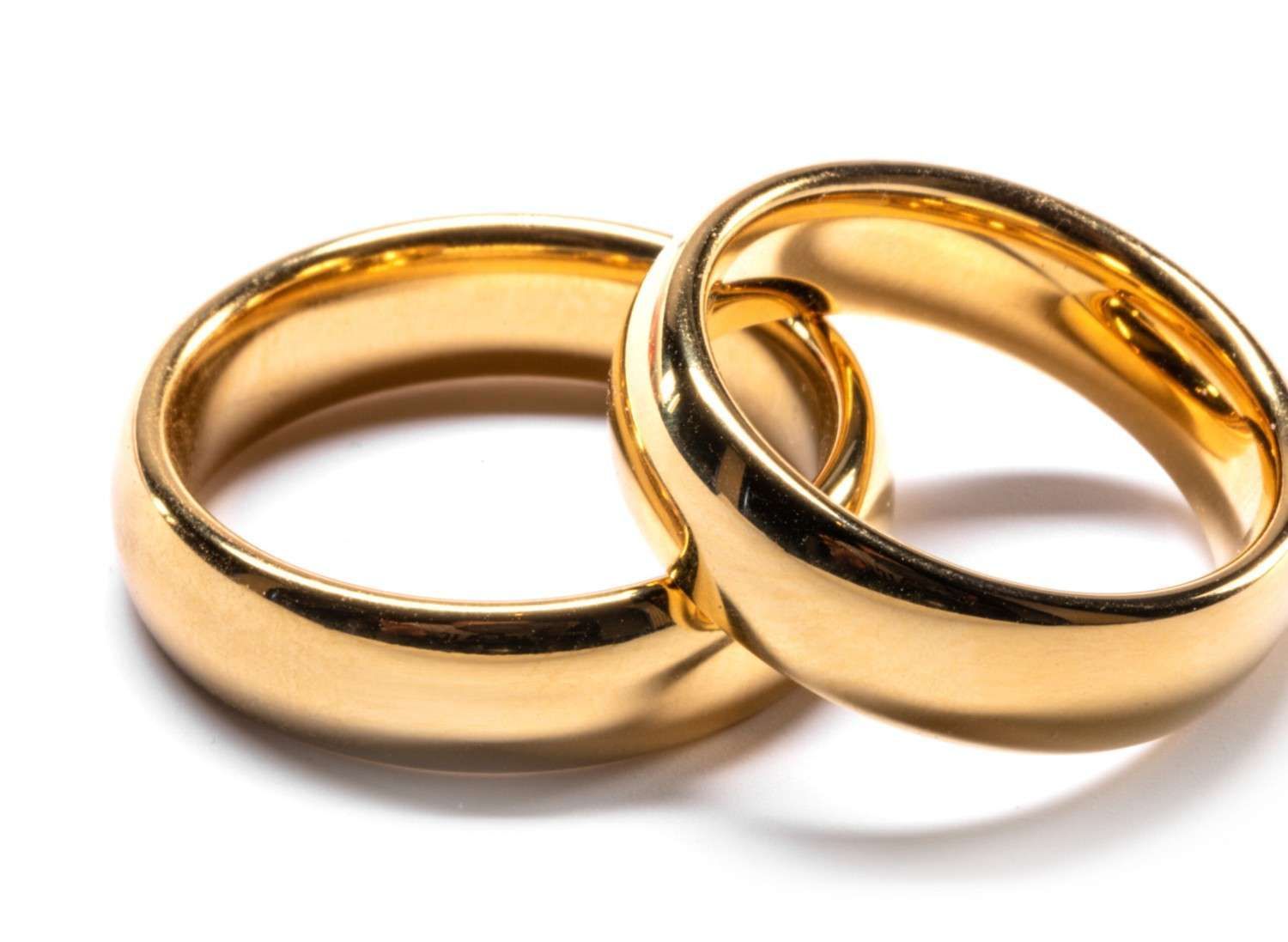 Dos anillos de boda de oro, entrelazados, sobre fondo blanco.