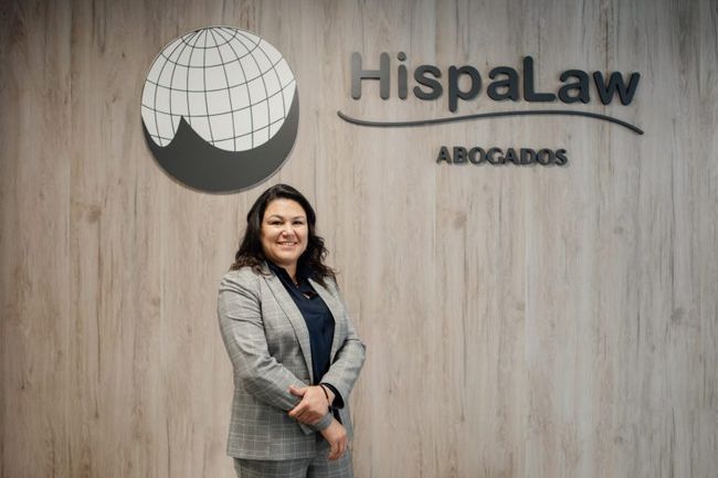 Una mujer con traje está parada frente a un cartel que dice