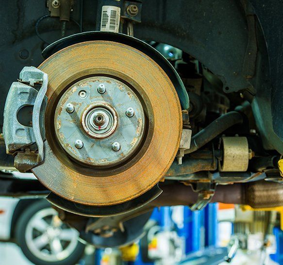 Primer plano del disco de freno y la pinza de un coche en un elevador de un taller mecánico