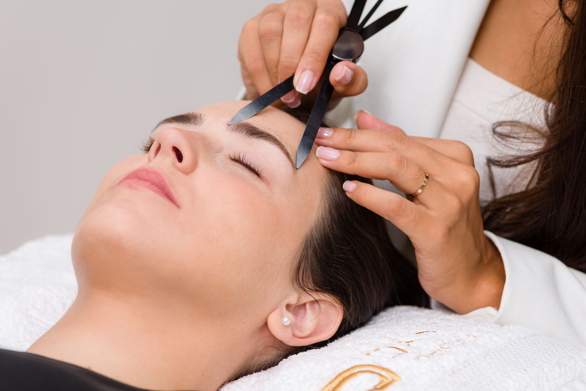 Una mujer se deja dibujar las cejas por un maquillador.