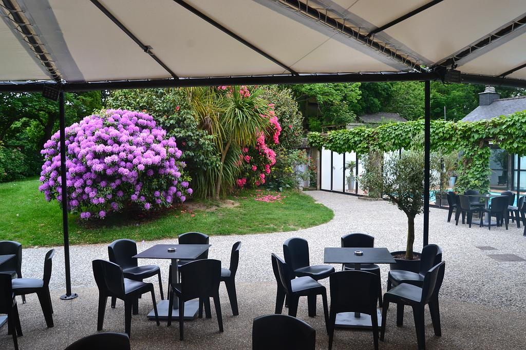 Tables et chaises en plastique noir sous une tonnelle